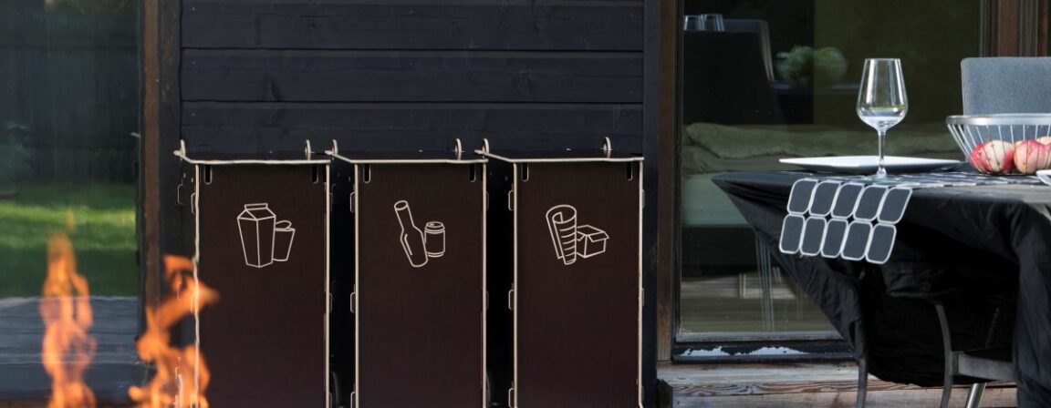 Eco-friendly outdoor waste sorting bins made from sustainable materials, placed on a wooden terrace near a home, symbolizing modern sustainable living.