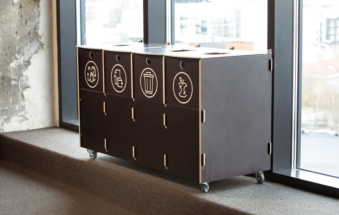 Recycling bins made of durable plywood with labeled sections for packaging, paper, mixed, and bio waste, placed in a modern office setting.