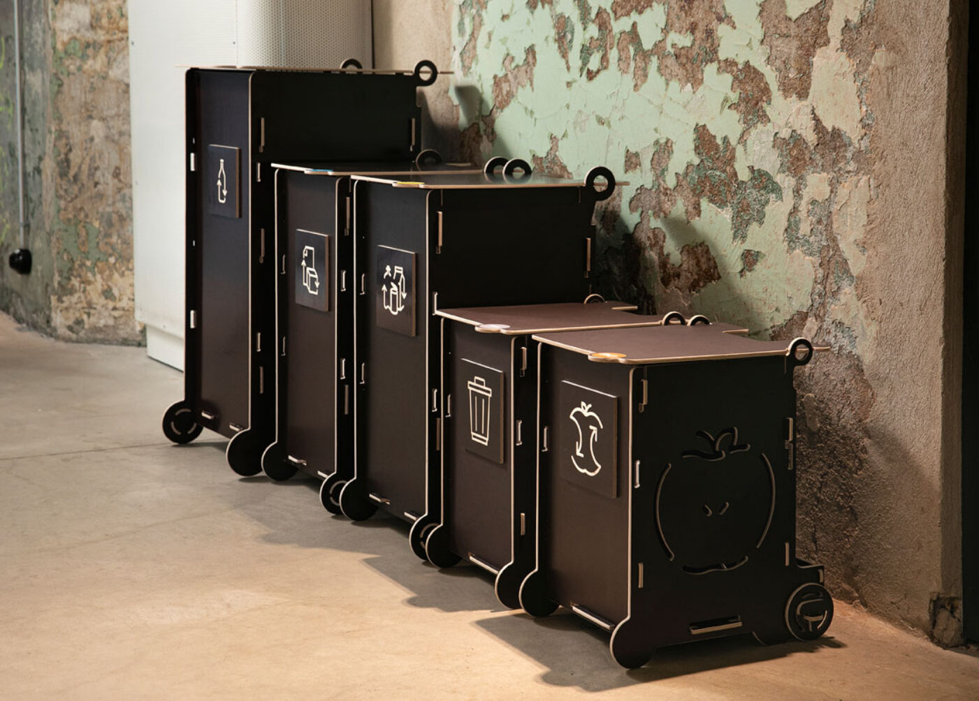 Black office waste bins with lids and recycling symbols, featuring separate sections for paper, packaging, mixed, and bio waste.