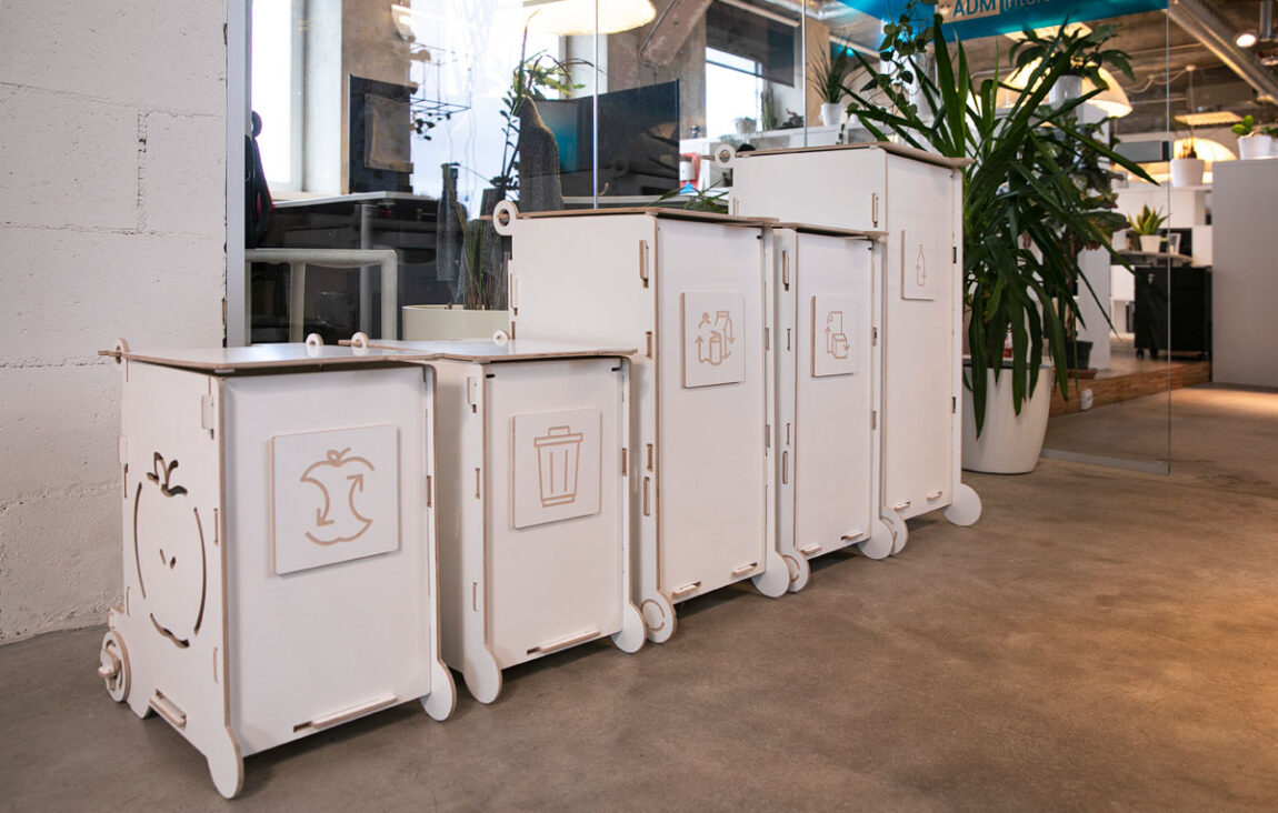 Modern white waste bins with lids and wheels, ideal for offices or public interiors, featuring separate sections for paper, packaging, and bio waste.