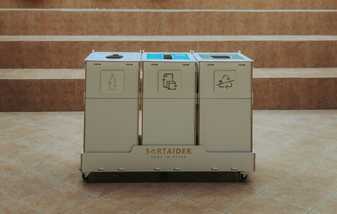 Recycling bins with instructional stickers helping staff sort materials correctly in an office.