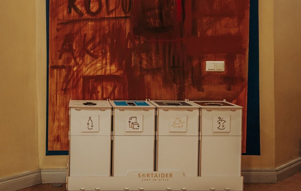 Recycling bins with lids in a shared indoor space to reduce odours and keep sorting areas tidy.