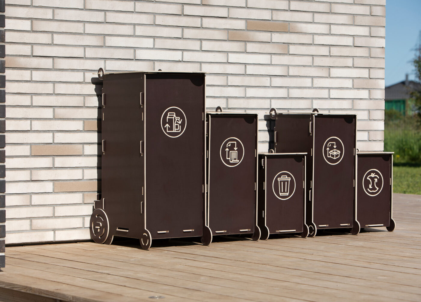 Modernit puiset kotitalousjätteiden roskakorit, joissa on erilliset osastot lasille, pakkausjätteille, sekajätteille ja biojätteille.