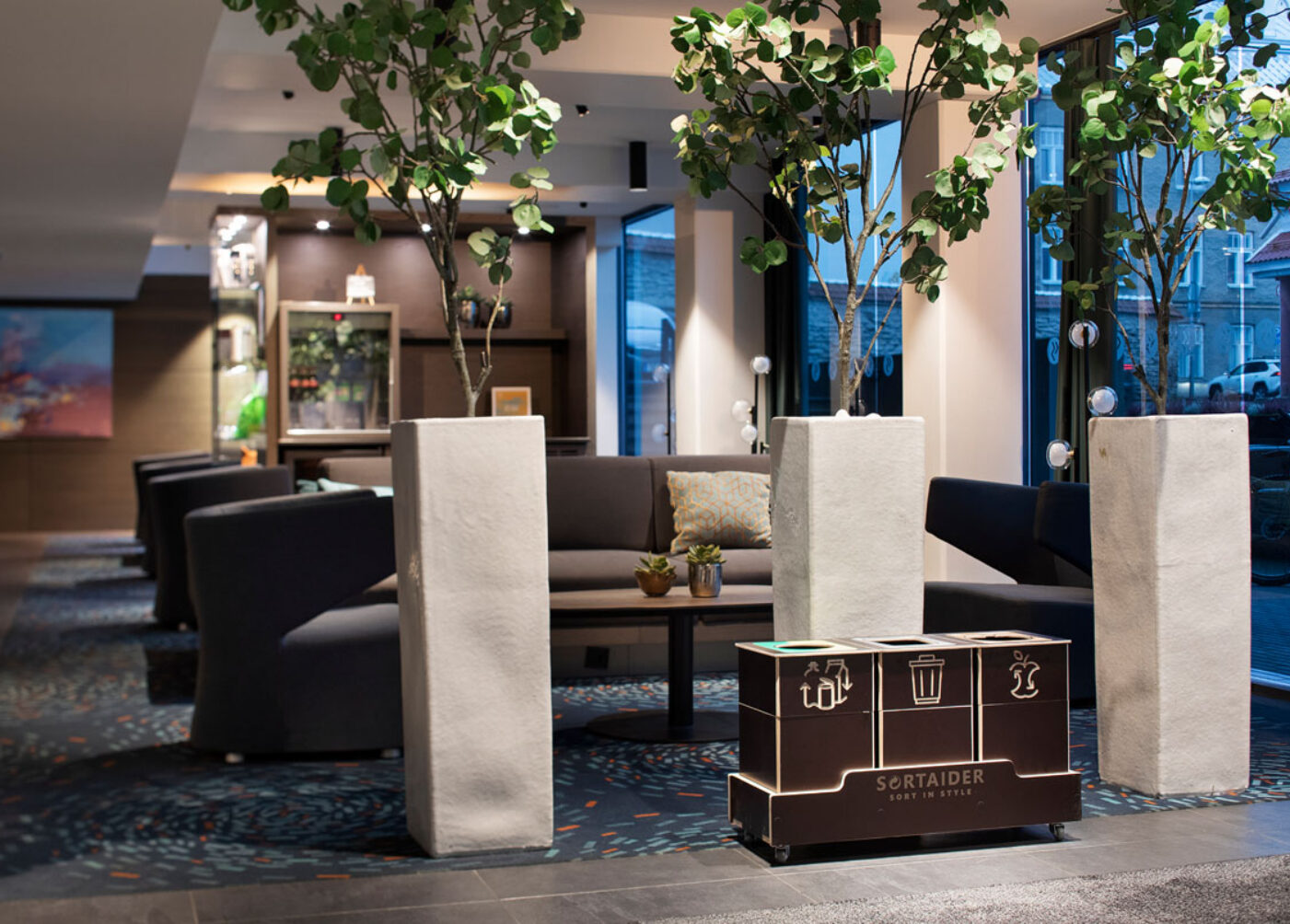 Kestävien toimistojen kierrätysastiat on sijoitettu yhteiseen työtilaan, jotta jätteiden lajittelu tuntuu vaivattomalta.