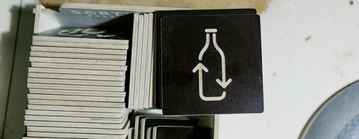 Nærbillede af holdbart krydsfinérmateriale, der bruges til fremstilling af genbrugsbeholdere, med højkvalitets trælag og indgraverede affaldssorteringssymboler.