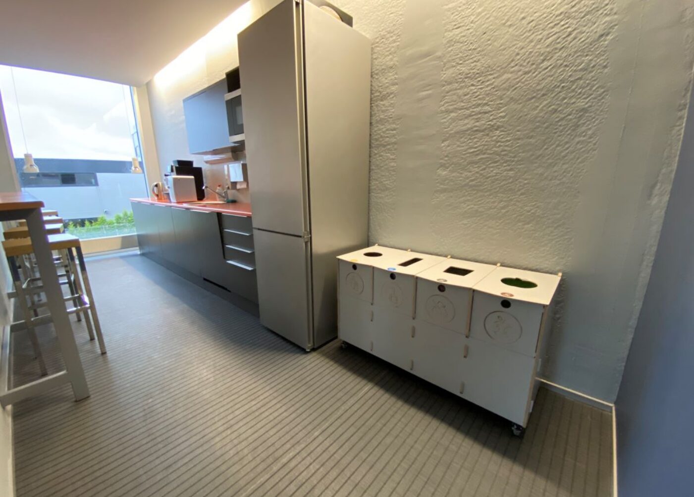 Papperskorgar för övergångsutrymmen på kontor placerade längs gångvägar för att underlätta intuitiv avfallssortering.