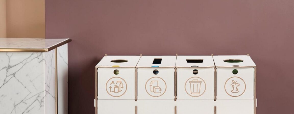 Hospitality recycling bins - white 4-compartment plywood sorting station on wheels next to a marble counter.