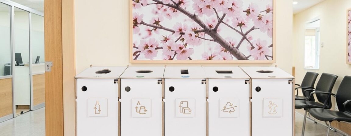 Indoor recycling bin. Five-compartment birch plywood sorting station on wheels in a bright waiting area.