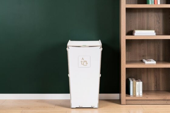 Public space waste bin. Laminated birch plywood waste bin beside a bookshelf in a lobby.