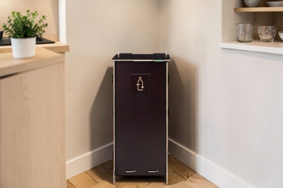 Waste bin - a durable choice for collecting a single waste fraction. Birch plywood bin for bottle collection in the corner of a modern space.